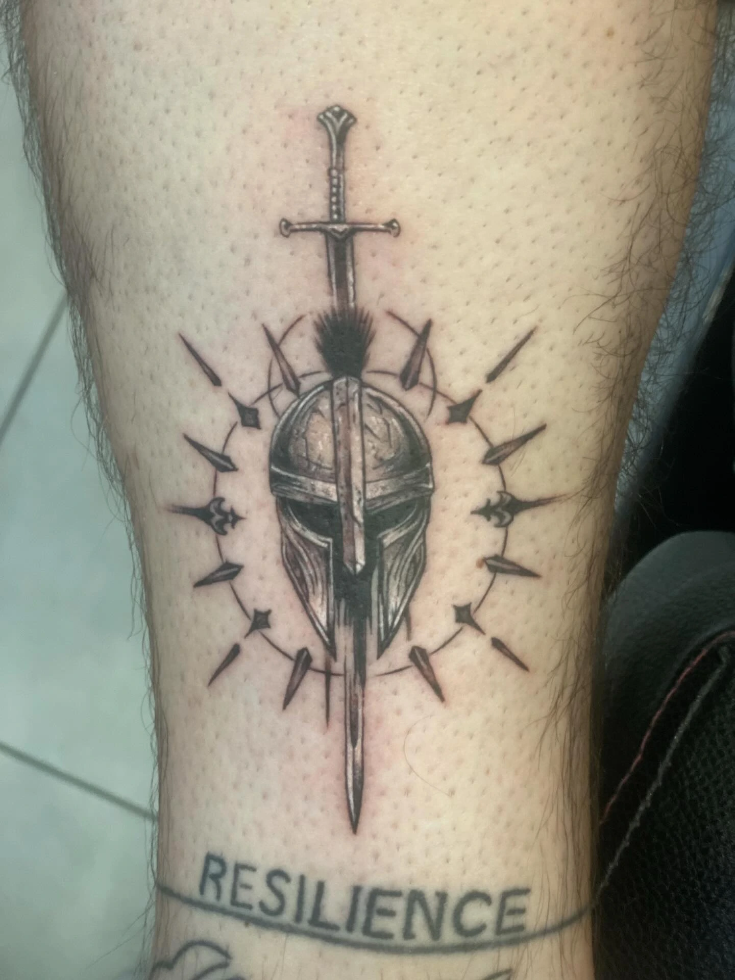 Spartan/Greek plumed helmet with linework hatching, palm-tree island scene above