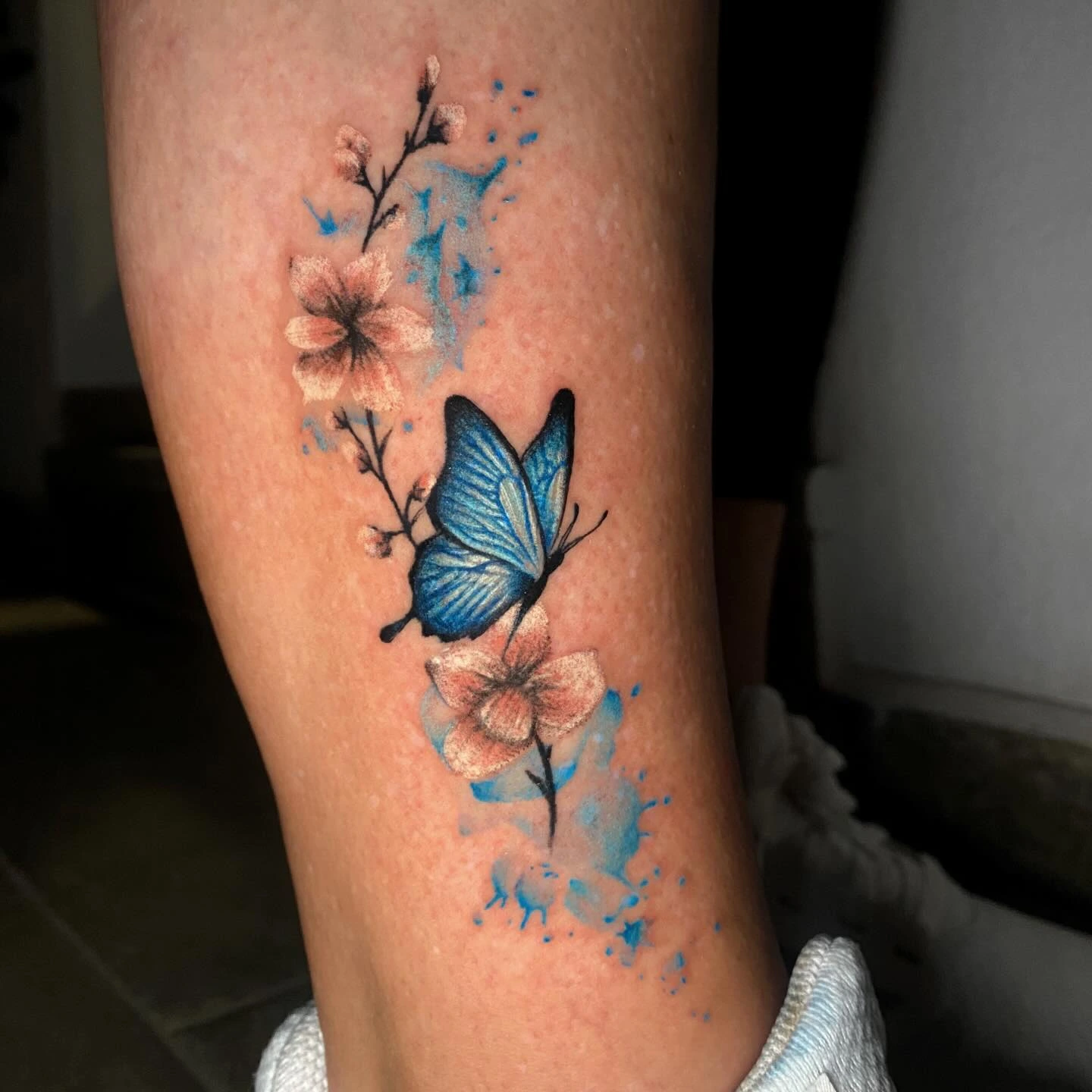 Cobalt blue butterfly with peach cherry-blossom branches and watercolor blue splatter