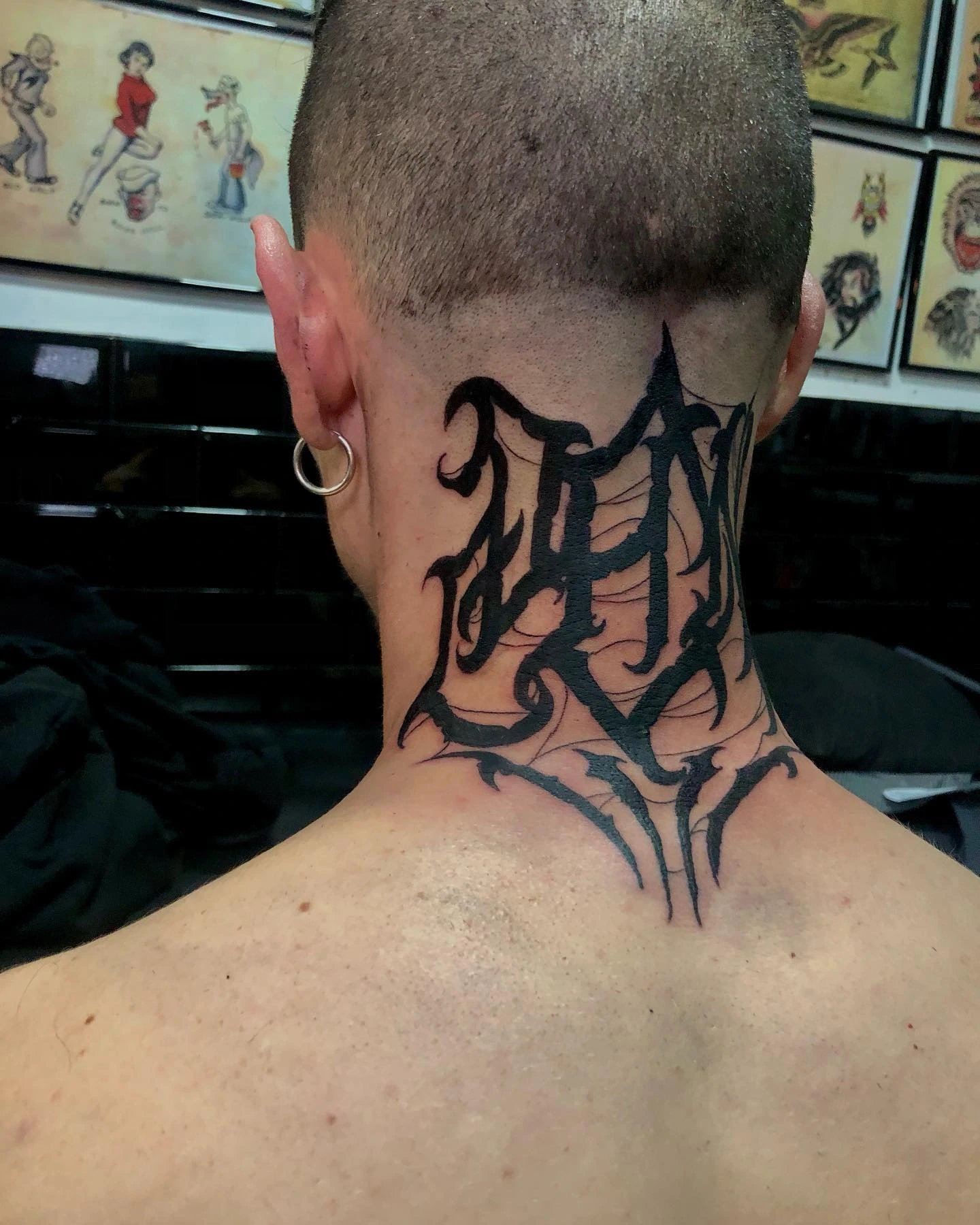 Blackletter / chicano-script lettering with web filigree on back of neck