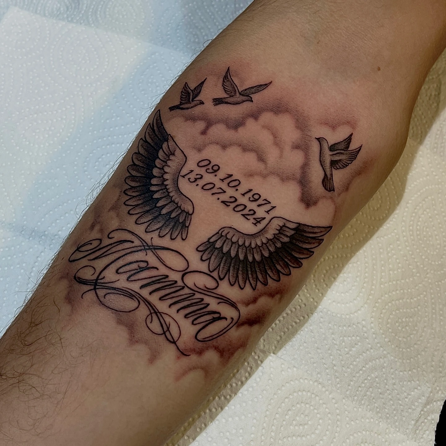Memorial 'Mamma' script with dates 09.10.1971 / 13.07.2024 and angel wings in clouds
