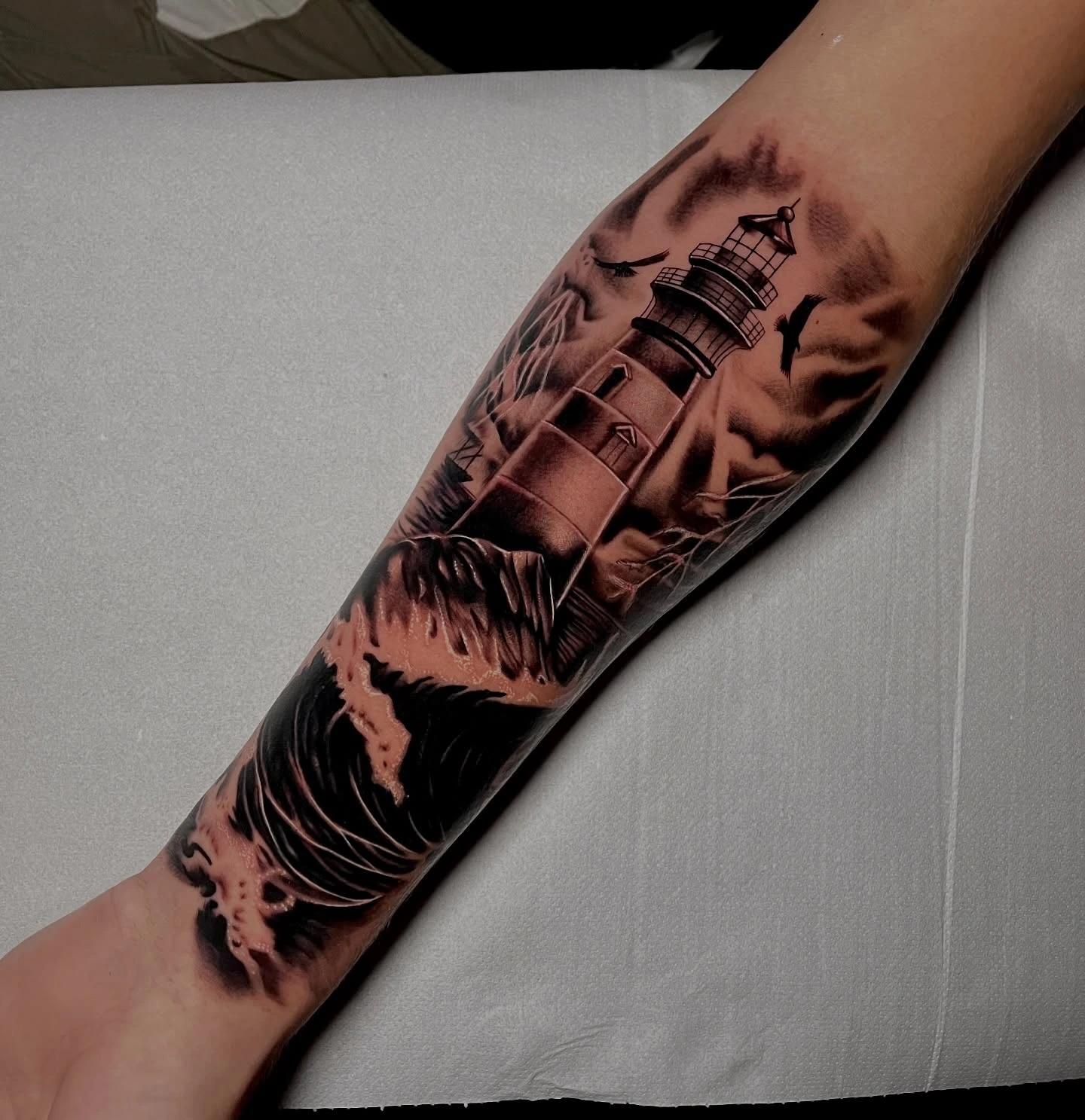 Lighthouse on cliff with crashing waves and birds