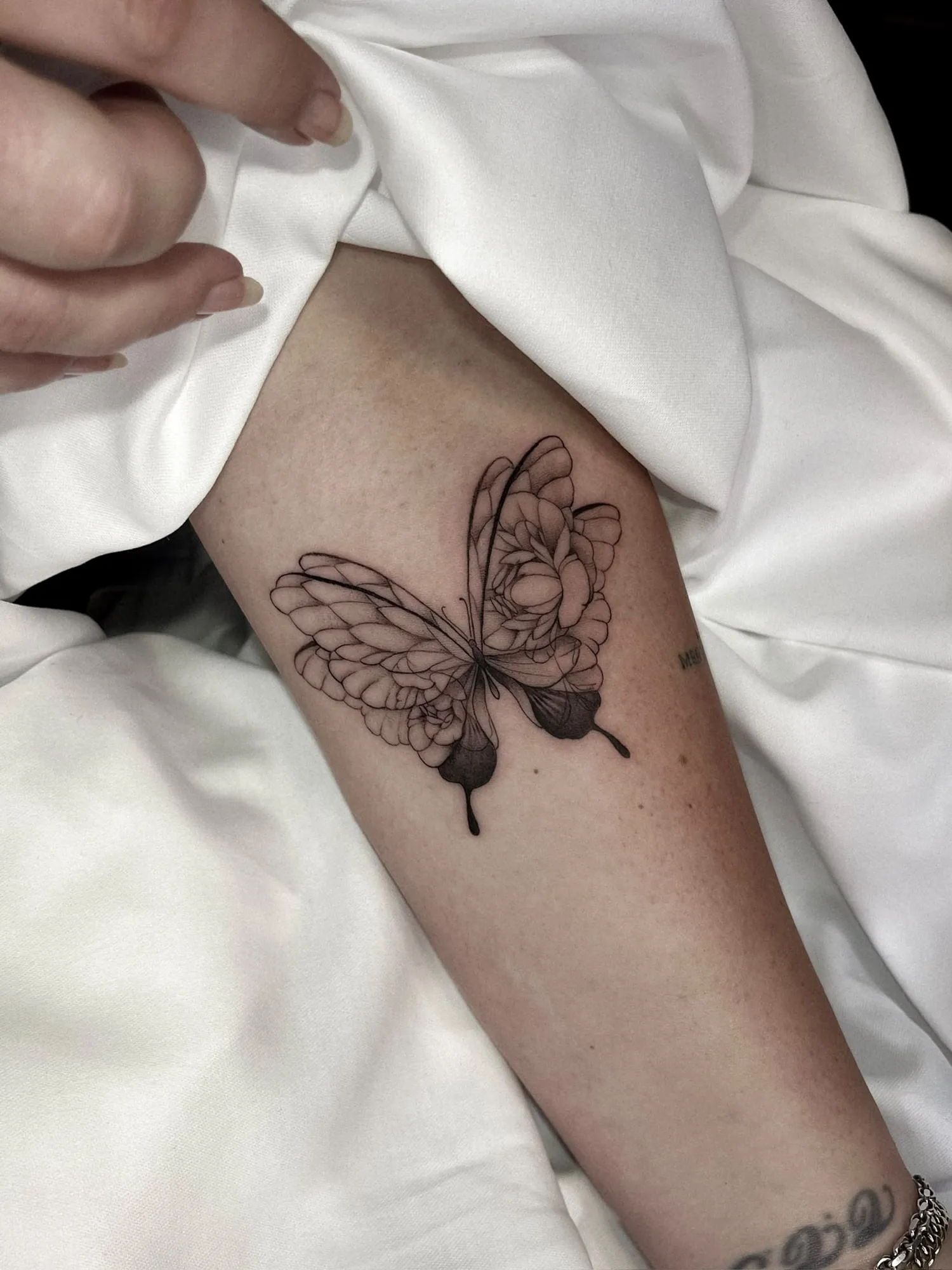 black & grey fineline butterfly with flower petals forming the wings on inner upper arm