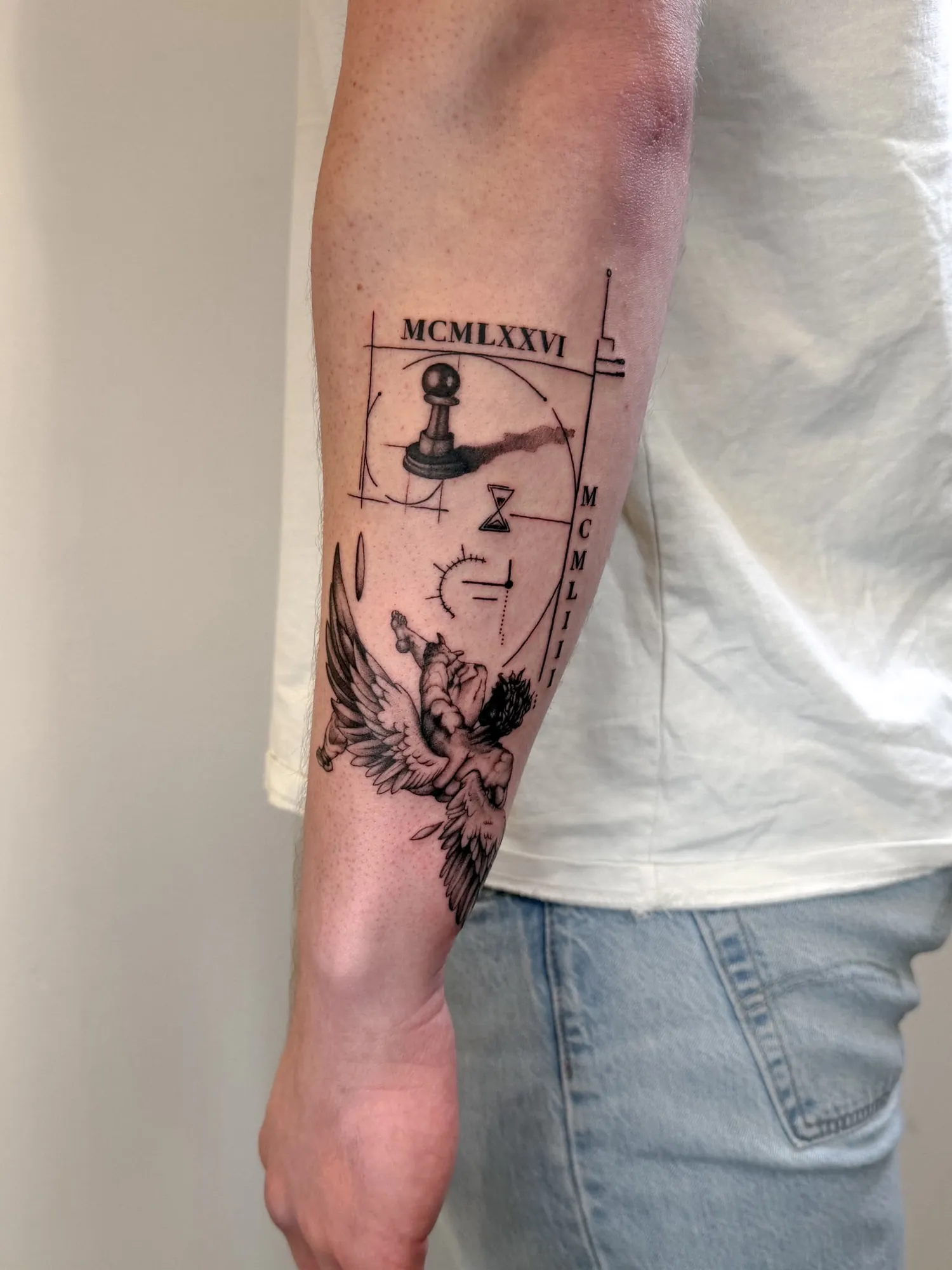 black & grey forearm composition with Roman numerals 'MCMLXXVI' and 'MCMLIII', a chess pawn, an hourglass, geometric construction lines and a falling winged figure