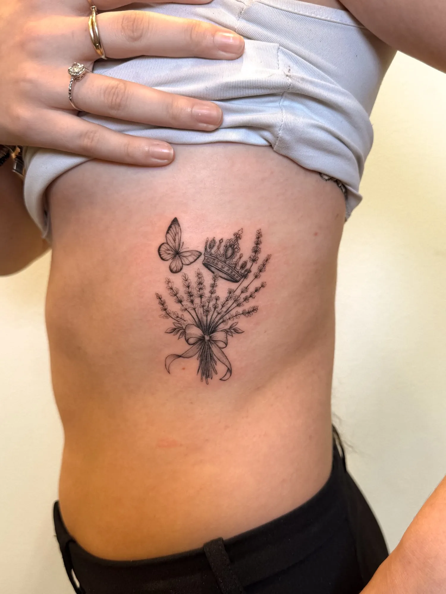 black & grey fineline bouquet of lavender sprigs tied with a ribbon bow, with a small butterfly and a crown above, on the ribs