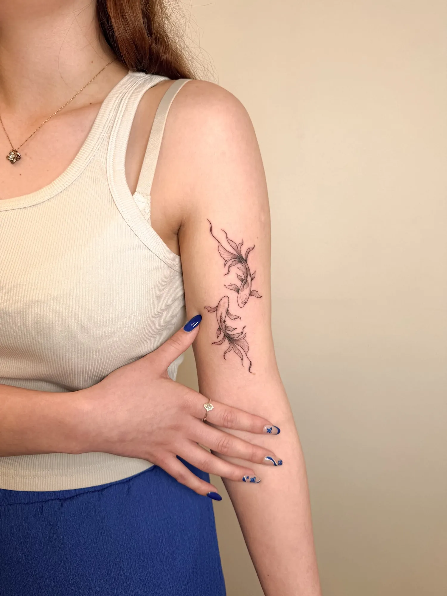two fineline black & grey koi / long-finned fish swimming in a circle on the back of the upper arm
