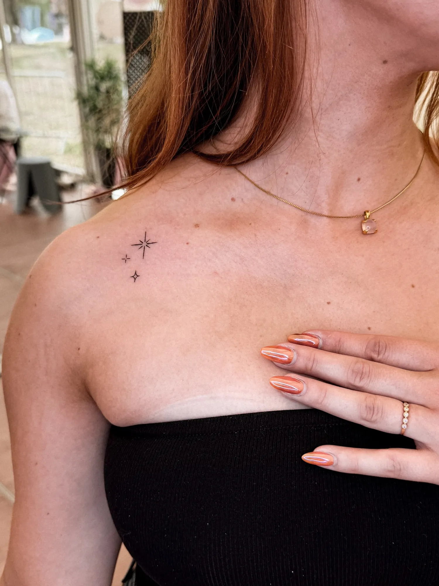 three tiny fineline sparkle stars of different sizes on front of shoulder near collarbone