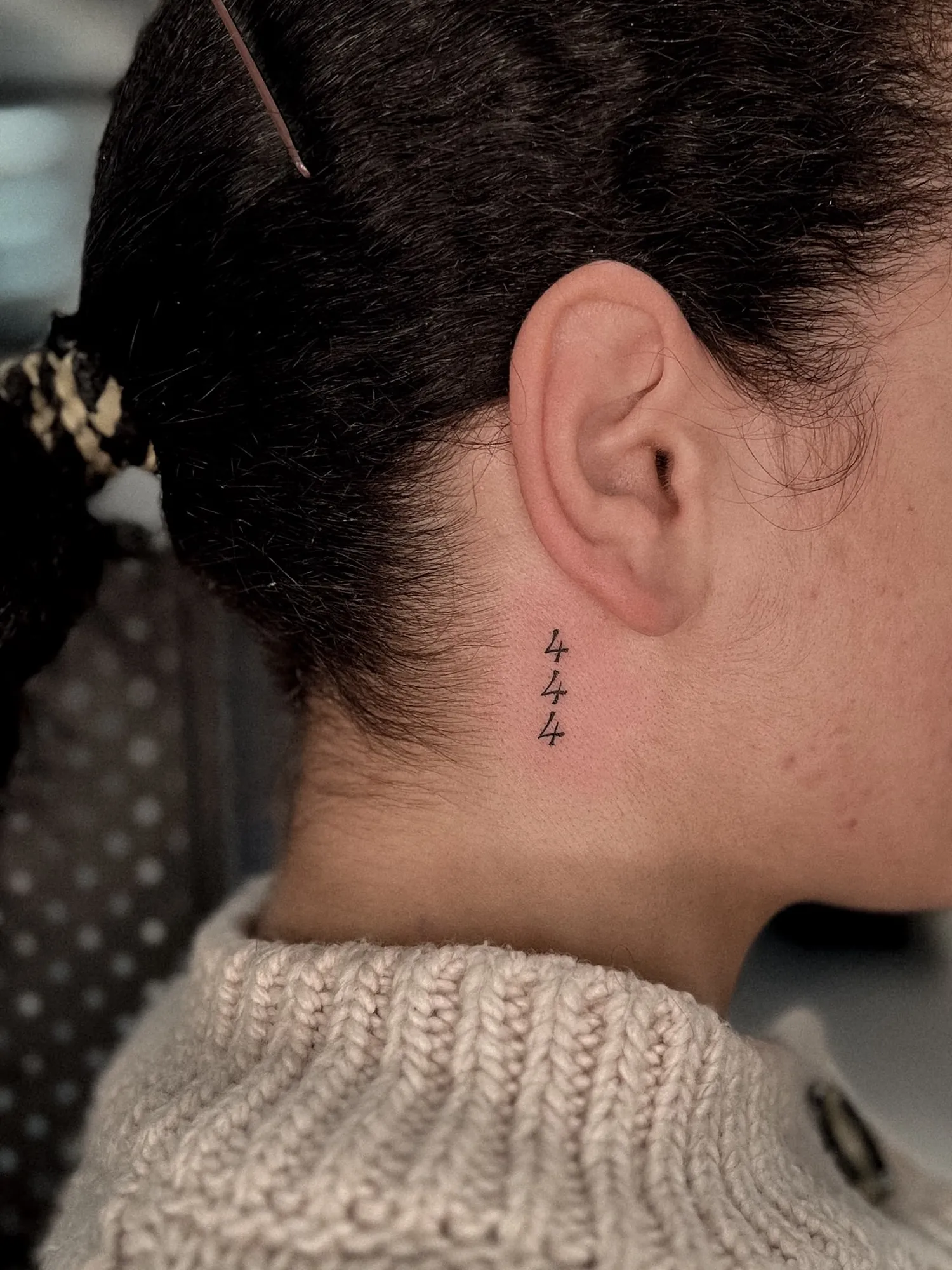 tiny stacked numerals '444' behind the ear