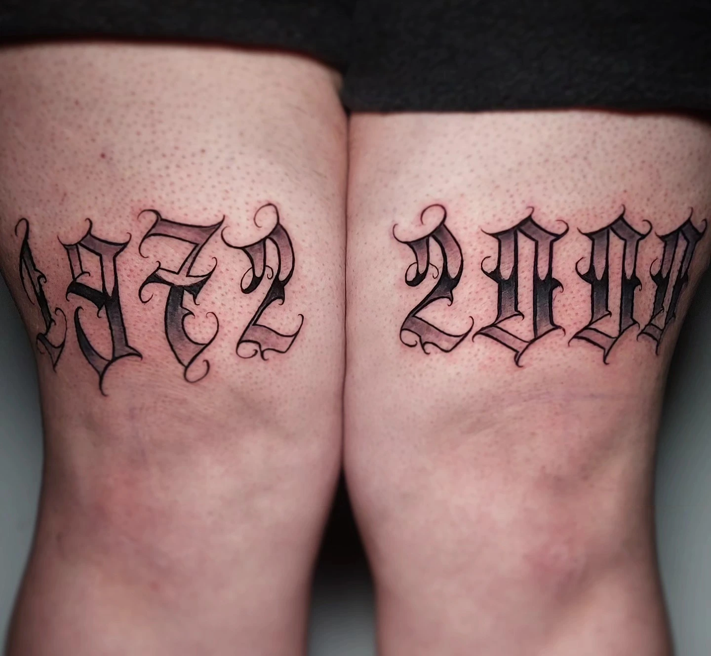 Paired Old English year numerals '1972' & '2000' on knees