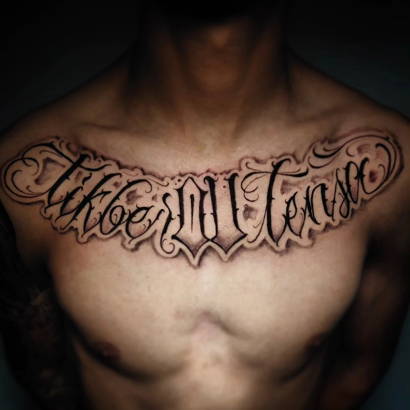 'Take Intense' (or similar) chicano filigree across collarbones