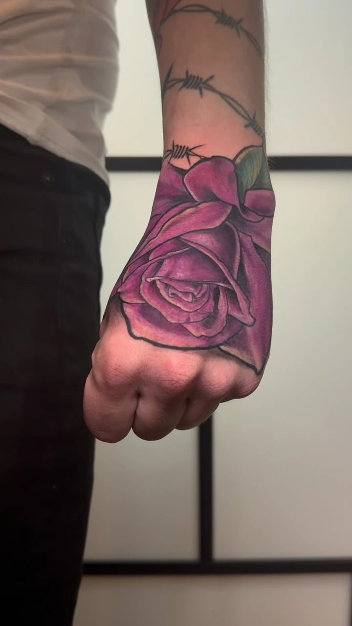 Saturated purple rose with barbed wire on hand/wrist