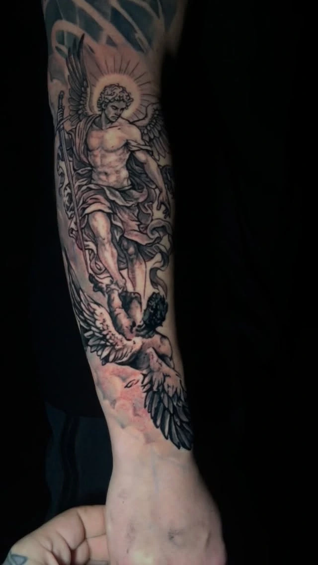 Archangel with sword and wings standing over fallen angel/demon